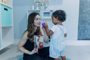 Fonoaudióloga brincando com criança pequena durante sessão de fonoaudiologia infantil